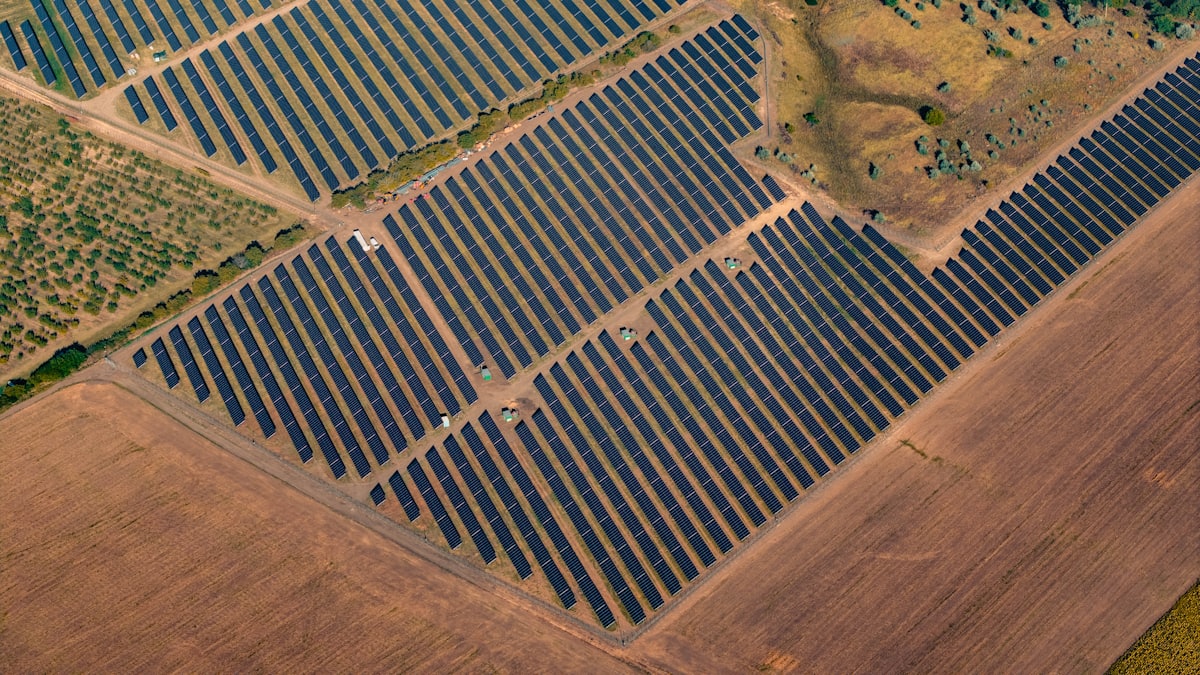 Aerial view of rows of solar panels in a large ground-mounted solar farm